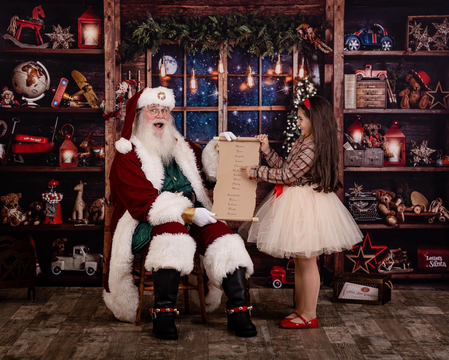 girl pointing to the nice list with santa claus during her Santa picture session in Raleigh North Carolina