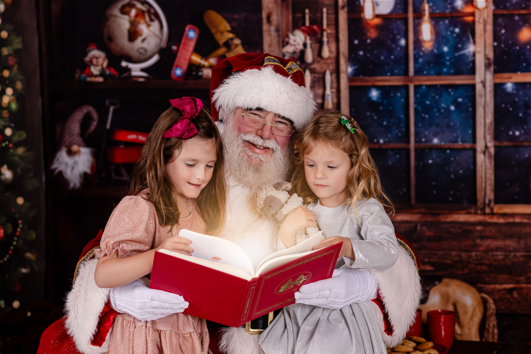 girls reading book with santa claus